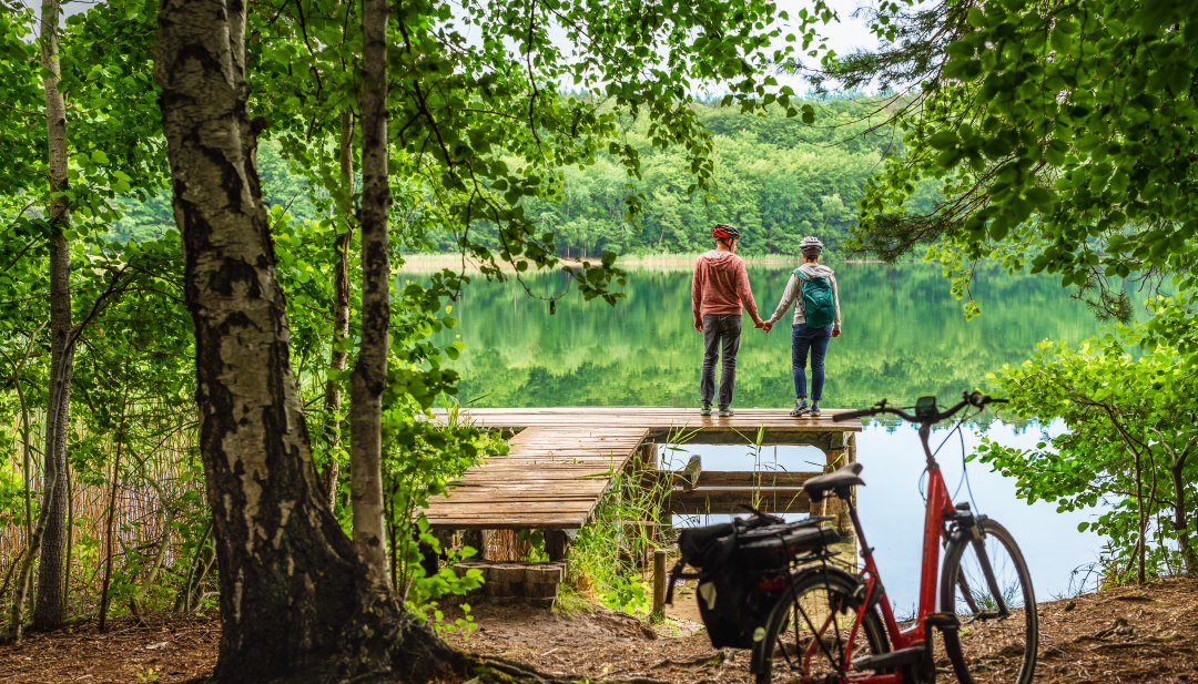 A couple with bicycles on Lake Woblitz take a break on a jetty.
