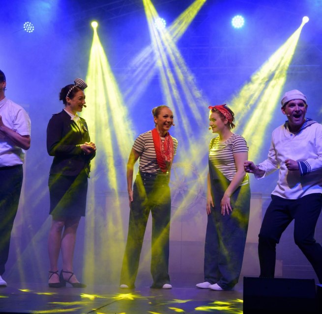 Aktorzy w strojach marynistycznych podczas rejsu na scenie Burgfestspiele Plau am See. // Porywający teatr muzyczny na scenie pod gołym niebem - Plau am See Castle Festival przenosi publiczność do morskich przygód i najlepszej wakacyjnej atmosfery dzięki humorystycznemu pokazowi rejsowemu. // © Tourist Info Plau am See GmbH/Diedrichsen Aktorzy w strojach marynistycznych podczas rejsu na scenie Burgfestspiele Plau am See.