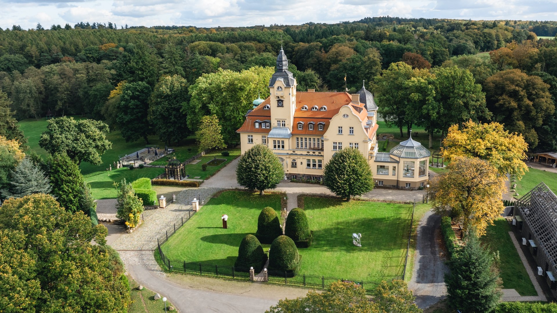 Luchtfoto van het amberkasteel Wendorf, omgeven door groene weiden en bomen onder een licht bewolkte hemel.