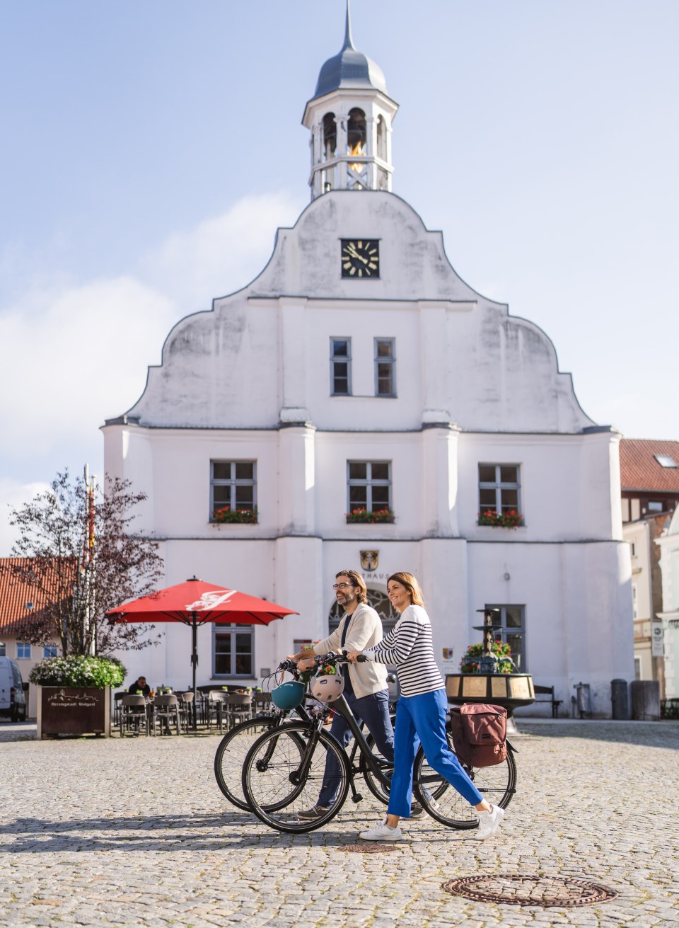 Two cyclists push their bikes across the market square in Wolgast