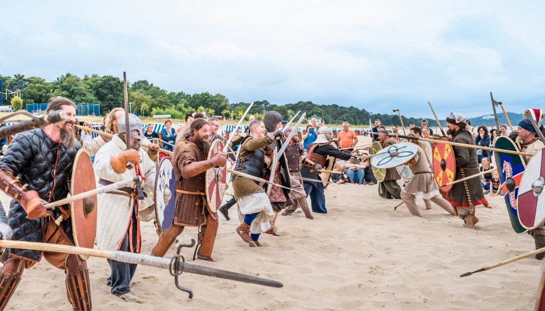 De "strandgevechten" tussen de clans zijn een van de hoogtepunten van het Vikingfestival van Göhren, © TMV/Tiemann Mensen verkleed als Vikingen rennen naar elkaar toe op het strand van Göhren