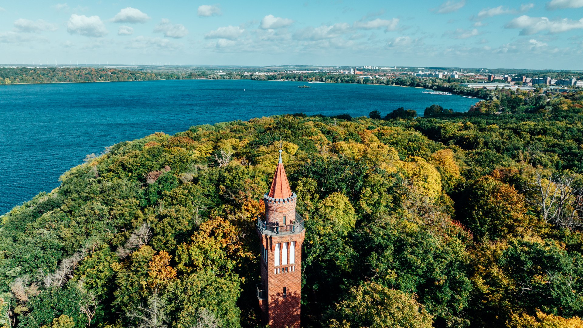 Szeroka panorama z wieży widokowej Behmshöhe nad jeziorem Tollensesee, wyglądająca z lasu z jeziorem w tle. // Robi wrażenie nawet na młodszych gościach: rozległa panorama z wieży widokowej Behmshöhe nad jeziorem Tollensesee // © MV-T/Gänsicke Szeroka panorama z wieży widokowej Behmshöhe nad jeziorem Tollensesee, wyglądająca z lasu z jeziorem w tle.