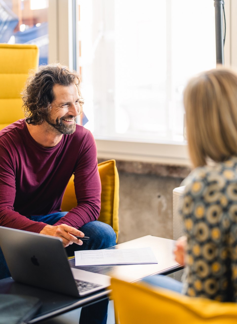  Three people in conversation in a cozy seating area at InnovationPort Wismar, a modern co-working space.