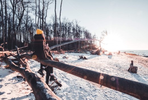 Dompel je onder in het rustige winterlandschap langs de besneeuwde Baltische kust bij Torfbrücke en voel de kracht van de natuur., © TMV/Scholz-Winter Twee mensen in winterkleding wandelen op een besneeuwd Oostzeestrand bij Torfbrücke bij zonsondergang.