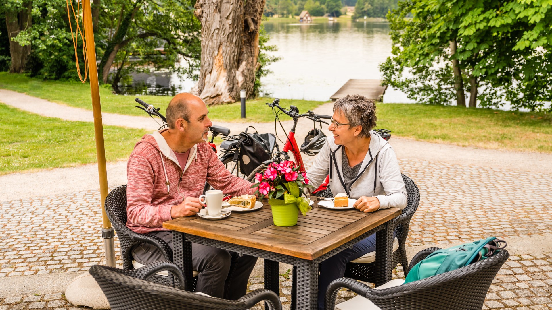 Een stel met koffie en gebak voor het kasteel van Mirow met het meer op de achtergrond
