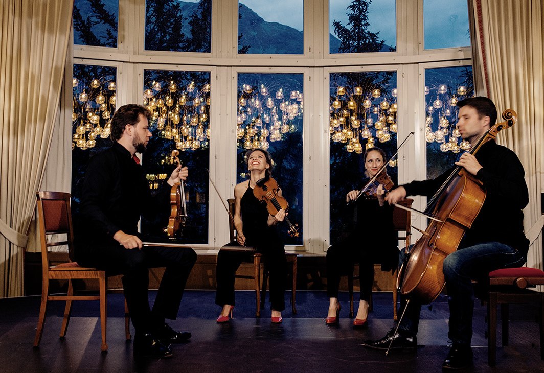 Four musicians with string instruments sit in front of a window wall, © Felix Bröde
