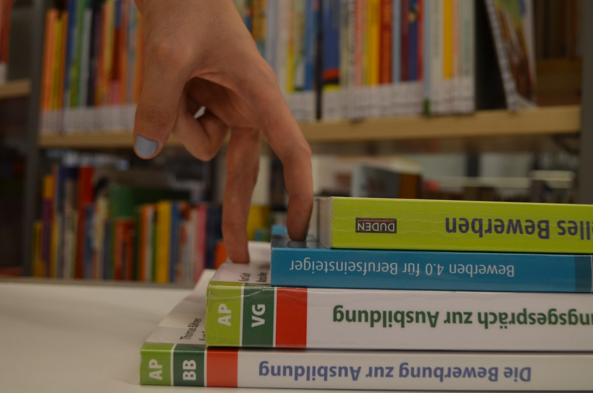 Dwa palce symbolicznie wspinają się po schodach wykonanych z książek, &copy; Stadtbibliothek Stralsund