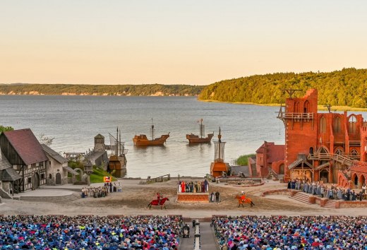 Stage of the Störtebeker Festival in Ralswiek on Rügen with audience, medieval backdrops and view of the Baltic Sea.
