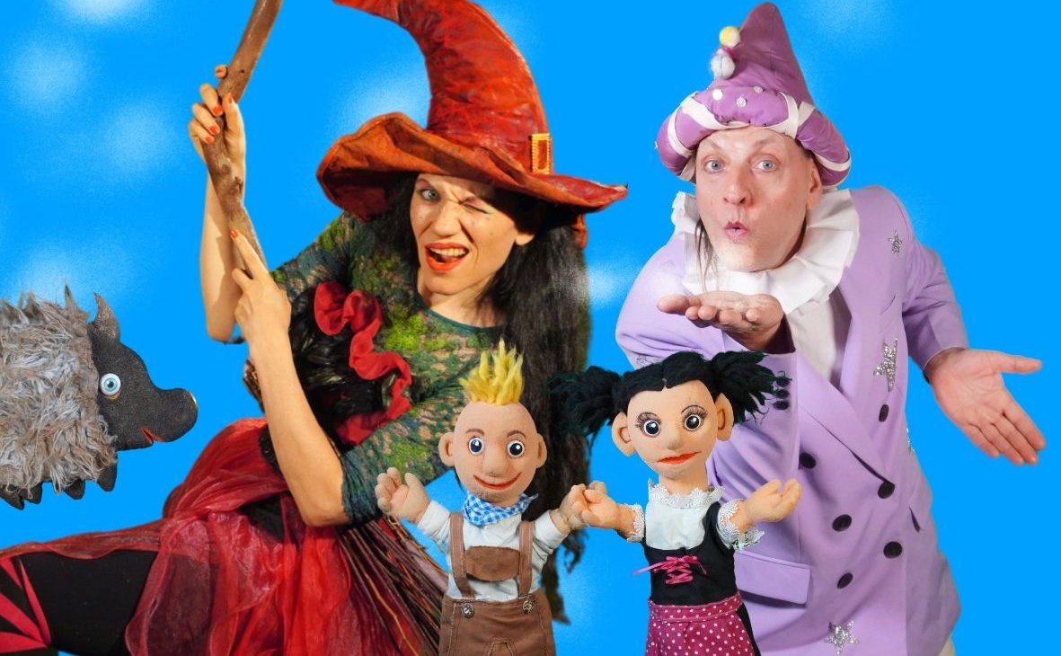 Twee poppenspelers verkleed als heks en tovenaar en twee handpoppen Hans en Grietje tegen een blauwe achtergrond, © Theater Phoebus