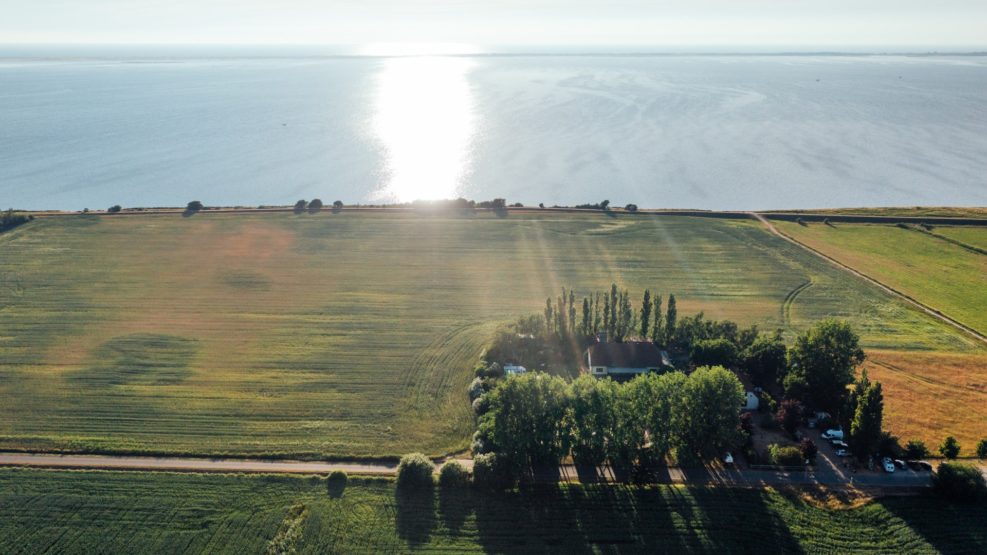 The Ummaii Surfhostel from the air with a view of the Baltic Sea at sunset