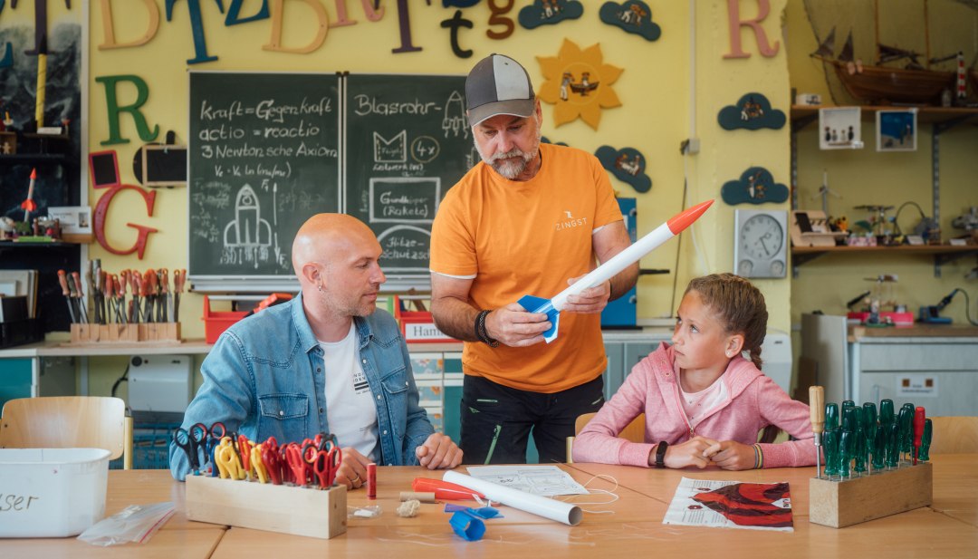 Et kursus på Experimentarium i Zingst – en person viser, hvordan en raket er bygget, til en far og hans datter, som skal bygge den selv. // I Experimentarium i Zingst udfolder Valea og hendes far deres kreativitet og bygger en raket. Så kan ferien begynde! // © MV-T/Petermann Et kursus på Experimentarium i Zingst – en person viser, hvordan en raket er bygget, til en far og hans datter, som skal bygge den selv.