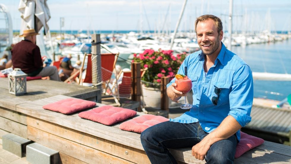 SOKO Wismar chief detective Lars Pöhlmann, alias Dominic Boeer, enjoys a cocktail in the boat harbor., © VMO, Alexander Rudolph