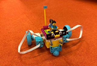 a small Lego robot with two Lego figures on it, orange background // &copy; Stadtbibliothek Stralsund