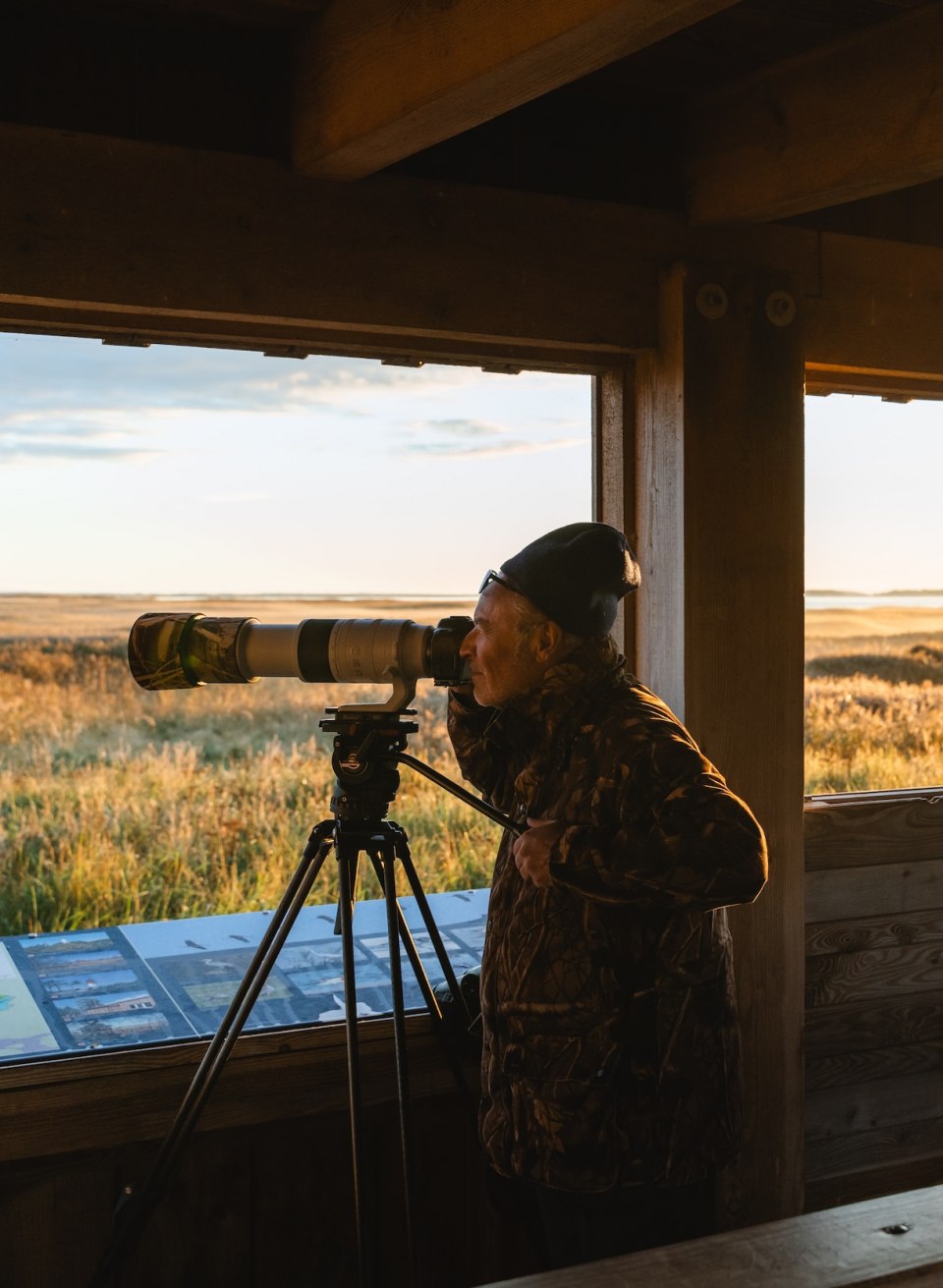  Dw&oacute;ch fotograf&oacute;w przyrody z aparatami i teleobiektywami na platformie obserwacyjnej o wschodzie słońca w parku narodowym.