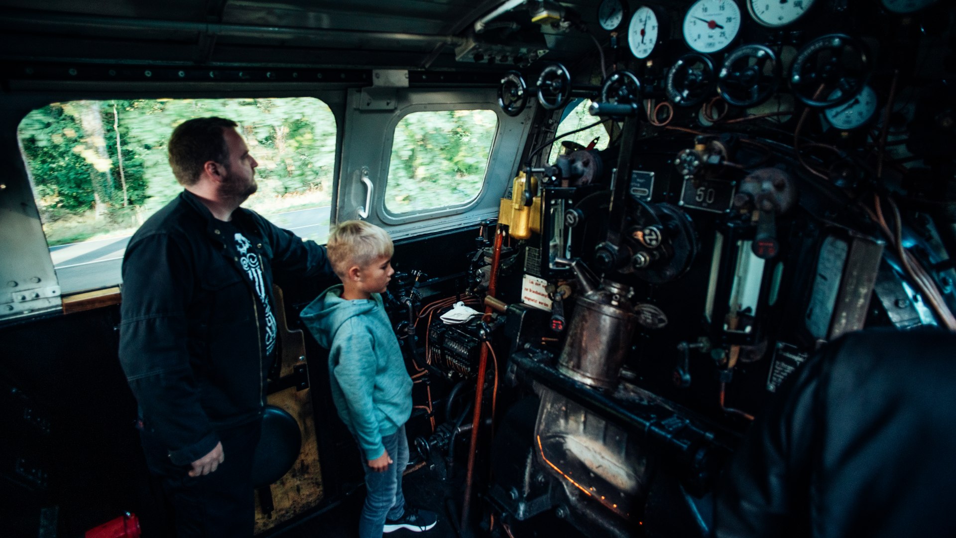 Een machinist van de Molli-B&auml;derbahn en een kind in de cabine met uitzicht op de ketel