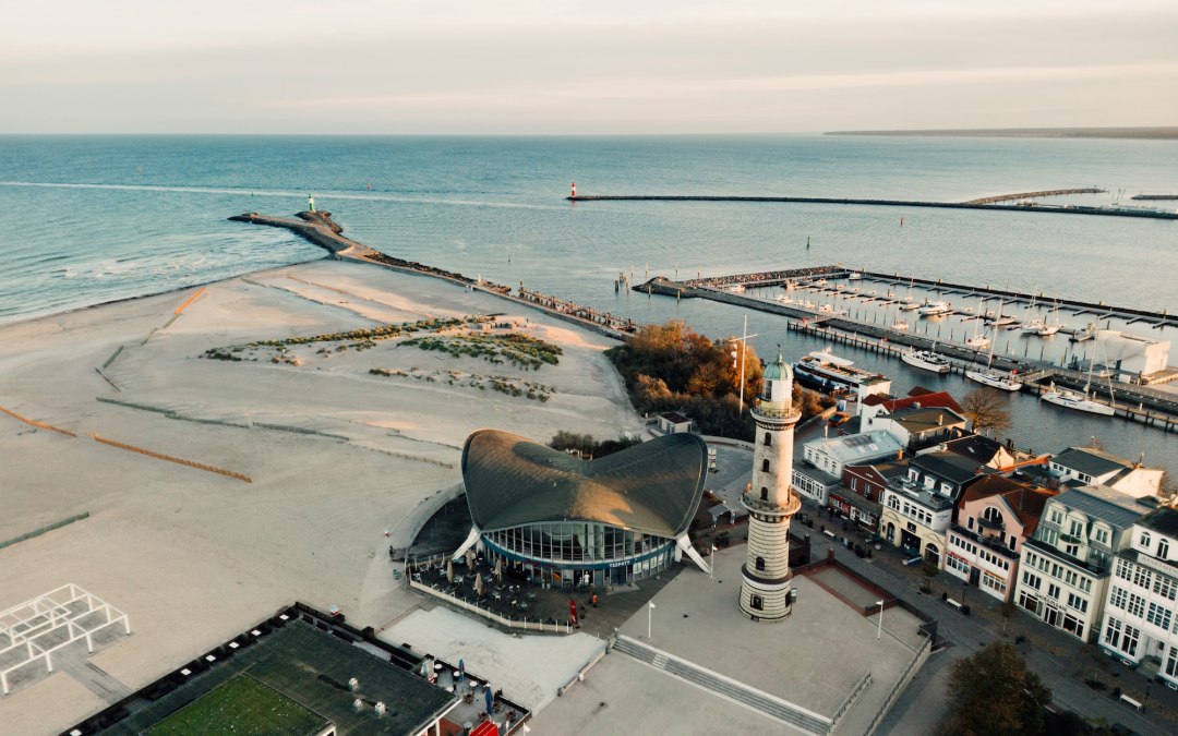 The harbor entrance to Rostock-Warnemünde is visible from the air: the lighthouse at the edge, the pier facing the Baltic Sea and numerous sailing boats in the water. Movement begins here from every angle. // © MV-T/Petermann The harbor entrance to Rostock-Warnemünde is visible from the air: the lighthouse at the edge, the pier facing the Baltic Sea and numerous sailing boats in the water. Movement begins here from every angle. // © MV-T/Petermann