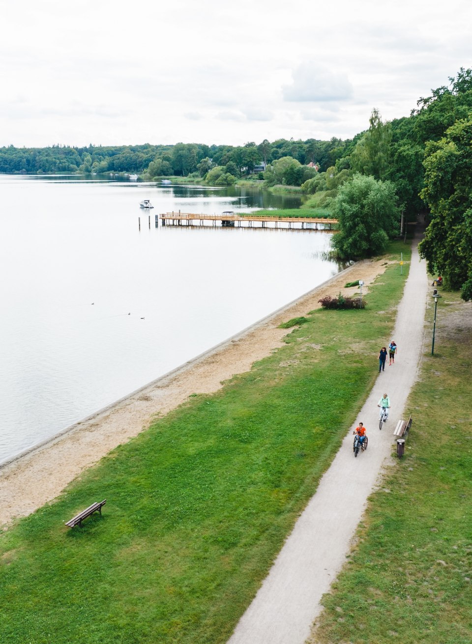 Een luchtfoto van een handbiker en fietser op een fietskoets op het Plau meer.