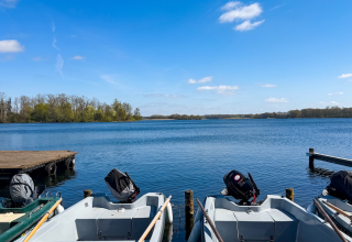 Blick vom Bootssteg über den Krakower See bei strahlendem Sonnenschein. Im Vordergrund liegen mehrere Ruder- und Motorboote der Bootsvermietung der Feriensiedlung Kiefernhain am Steg, Im Hintergrund erstreckt sich die weite, ruhige Wasserfläche mit bewaldeten Ufern. // © Feriensiedlung Kiefernhain Blick vom Bootssteg über den Krakower See bei strahlendem Sonnenschein. Im Vordergrund liegen mehrere Ruder- und Motorboote der Bootsvermietung der Feriensiedlung Kiefernhain am Steg, Im Hintergrund erstreckt sich die weite, ruhige Wasserfläche mit bewaldeten Ufern. // © Feriensiedlung Kiefernhain