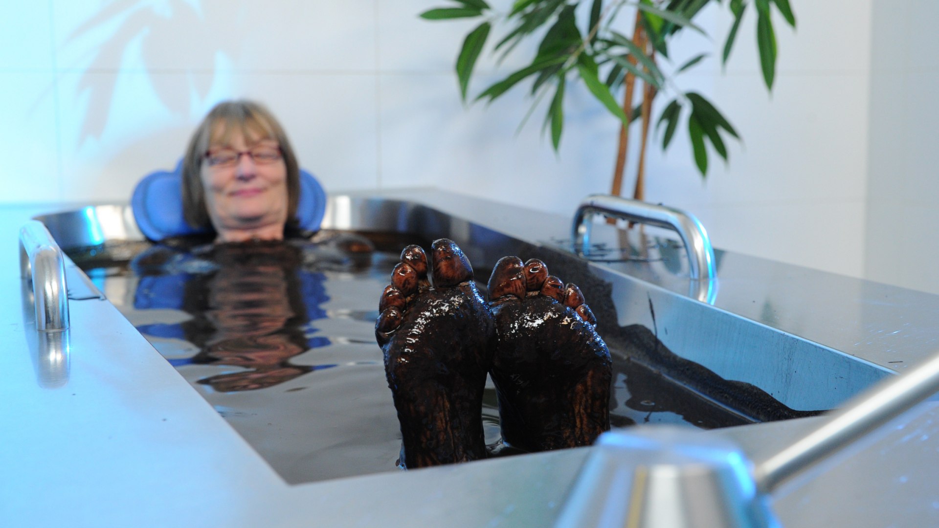 Natuurlijk modderbad in een speciaal bad - een vrouw neemt er een ontspannend bad in.