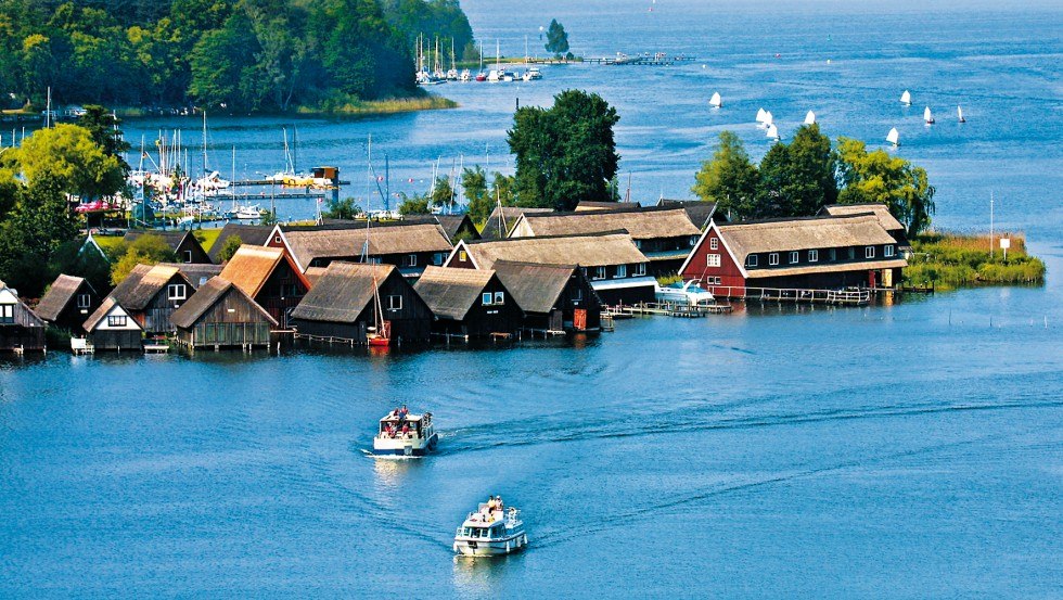 Embedded in a beautiful forest and lake landscape, the R&ouml;bel Bay appears with its small fishing cottages and sailboats. // &copy; TMV/Kuhnle Tours