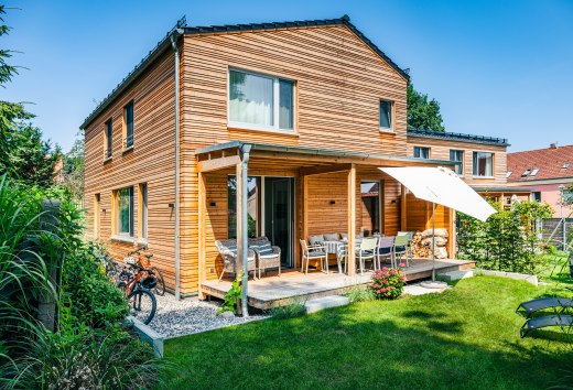 Een vakantiehuis met houten lambrisering en een groene weide ervoor.