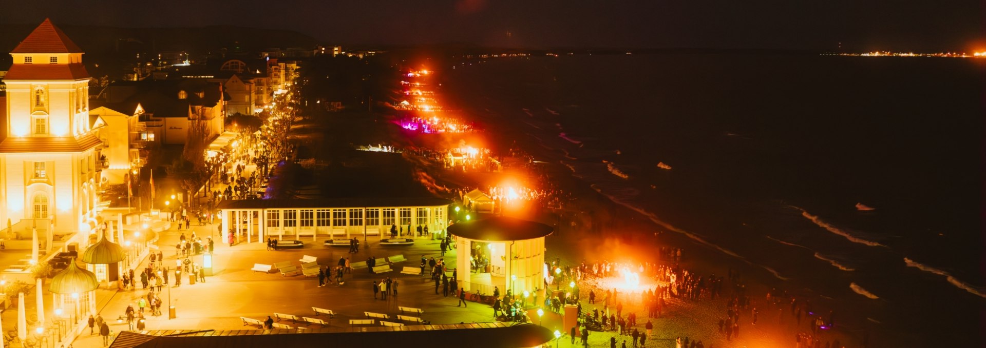 Nachtopname van de paasvuurmijl in Binz met verlichte strandpromenade en vuurkorven.