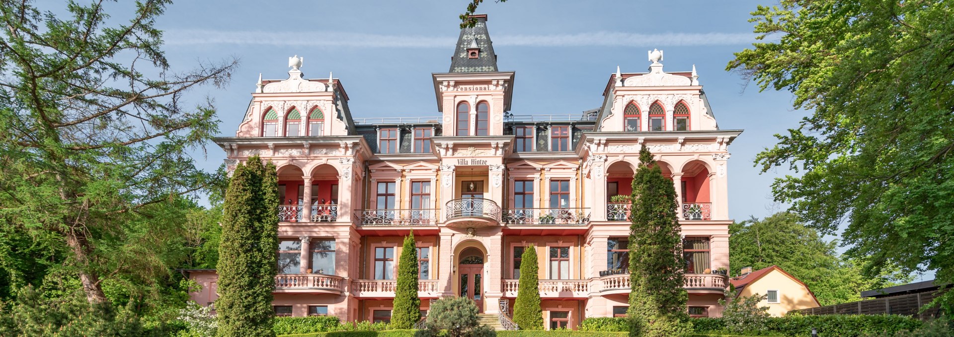 Zabytkowa willa w stylu architektury uzdrowiskowej na wyspie Uznam z ozdobnymi fasadami i zadbanym ogrodem frontowym.