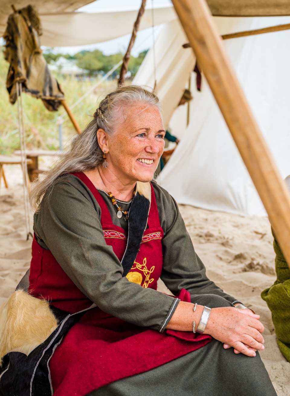 Een Vikingvrouw zit op het strand van het Vikingfestival in Göhren in haar typische kleding.