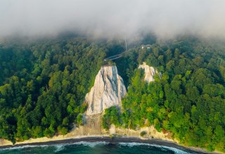 Eine beeindruckende Steilk&uuml;ste mit wei&szlig;en Kreidefelsen, dicht bewaldeten H&auml;ngen und dem Meer im Vordergrund. // &copy; Nationalpark-Zentrum K&Ouml;NIGSSTUHL / Dan Petermann