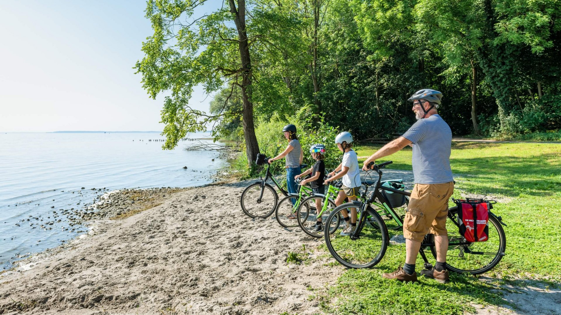 Een familie met fietsen staat bij een zwemplek aan het Plau meer