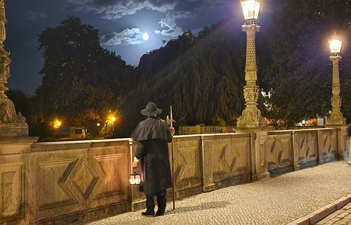 Nocny stróż na moście patrzący w stronę zamku nocą., © Michael Kratt