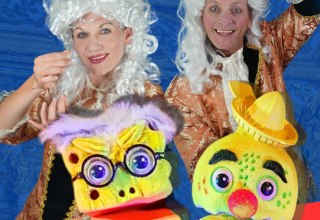 Kobieta i mężczyzna w cesarskich strojach i białej barokowej peruce trzymają nieprzezroczyste ubrania. // © Theater Phoebus Kobieta i mężczyzna w cesarskich strojach i białej barokowej peruce trzymają nieprzezroczyste ubrania. // © Theater Phoebus