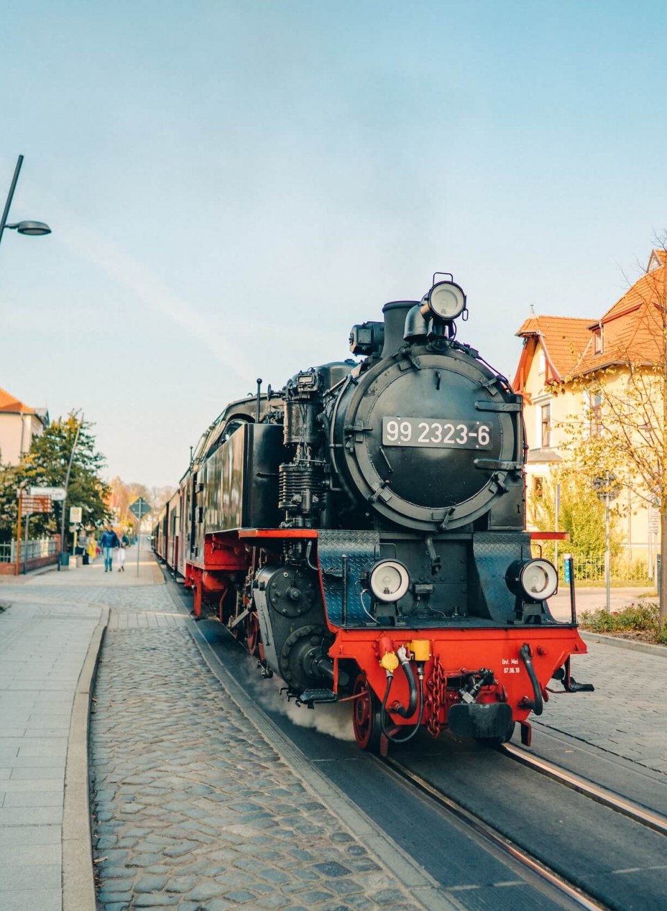 The Mecklenburgische B&auml;derbahn "Molli" steam train in the center of Bad Doberan, surrounded by houses and strollers.