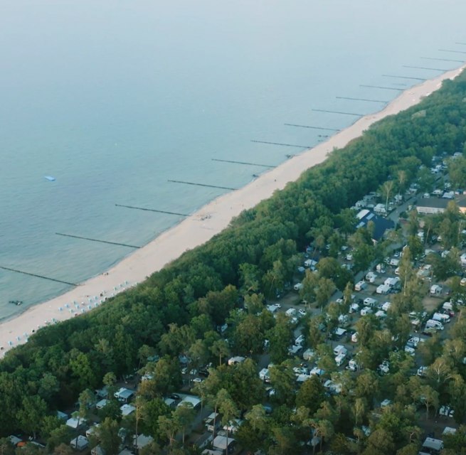 Luchtfoto van een camping aan de Oostzeekust met aangrenzend zandstrand en strandhoofden in zee. // Puur natuur en het geluid van de zee - camping direct aan het fijne zandstrand van de Oostzee. Perfect voor een ontspannen vakantie midden in de natuur met directe toegang tot de zee. // © TMV Luchtfoto van een camping aan de Oostzeekust met aangrenzend zandstrand en strandhoofden in zee.