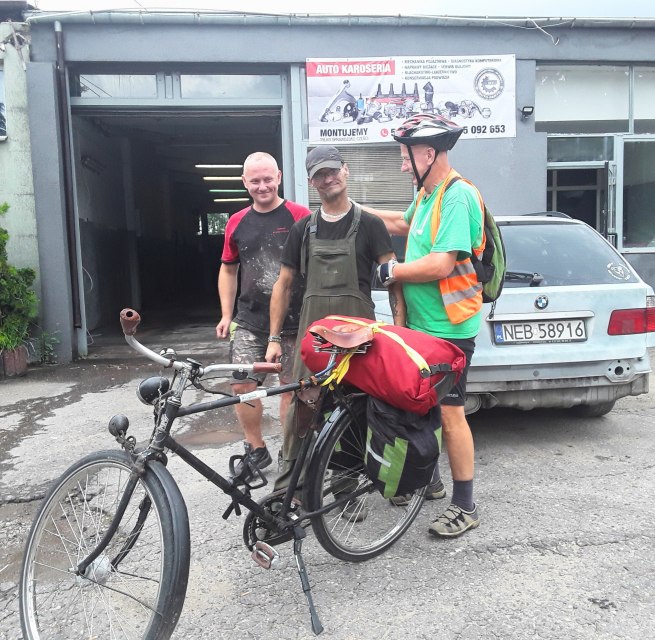 In the foreground a bicycle with red luggage, behind it Reinhard Klette with two Polish citizens. // &copy; Reinhard Klette