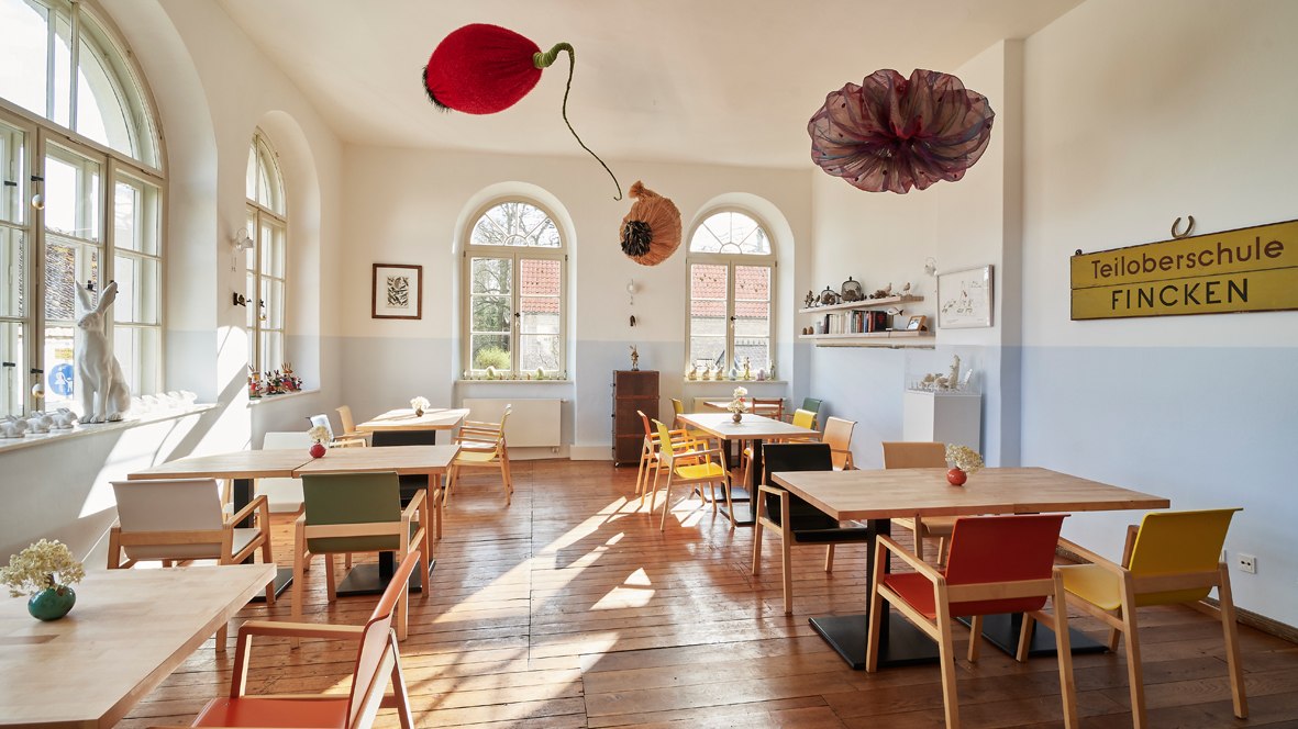 Het restaurant „Klassenzimmer“ is gevestigd in een van de voormalige klaslokalen van de Teiloberschule Fincken, die meer dan 60 jaar lang het Kavaliershaus van Schloss Blücher met leven vulde. Kunstwerken van twee Oostenrijkse kunstenaressen maken nu deel uit van de zichtbare (ge)schiedenis van het gebouw: De kinetische sculptuur van Theres Cassini (Verbotene Früchte) vult de ruimte met zachte, voortdurende bewegingen en het werk van Deborah Sengl (uit de serie Karl Kraus: De laatste dagen van de mensheid) verbindt het vroegere met het nieuwe gebruik: een klas in taxidermie leert de zin in Sütterlin-schrift op het bord: Zorg voor het toerisme – onze taak op deze plek met een buitengewone, regionale, verse keuken van nog een kunstenaar, de Mecklenburgse Gunnar Müller, die elk jaar iets nieuws creëert, en zo het tweede voormalige klaslokaal blijft gebruiken als plek om te leren en dit liefdevol weet over te brengen in elk detail, in elk ingrediënt van zijn gerechten! // © Henryk Weiffenbach / Kavaliershaus Het restaurant „Klassenzimmer“ is gevestigd in een van de voormalige klaslokalen van de Teiloberschule Fincken, die meer dan 60 jaar lang het Kavaliershaus van Schloss Blücher met leven vulde. Kunstwerken van twee Oostenrijkse kunstenaressen maken nu deel uit van de zichtbare (ge)schiedenis van het gebouw: De kinetische sculptuur van Theres Cassini (Verbotene Früchte) vult de ruimte met zachte, voortdurende bewegingen en het werk van Deborah Sengl (uit de serie Karl Kraus: De laatste dagen van de mensheid) verbindt het vroegere met het nieuwe gebruik: een klas in taxidermie leert de zin in Sütterlin-schrift op het bord: Zorg voor het toerisme – onze taak op deze plek met een buitengewone, regionale, verse keuken van nog een kunstenaar, de Mecklenburgse Gunnar Müller, die elk jaar iets nieuws creëert, en zo het tweede voormalige klaslokaal blijft gebruiken als plek om te leren en dit liefdevol weet over te brengen in elk detail, in elk ingrediënt van zijn gerechten! // © Henryk Weiffenbach / Kavaliershaus