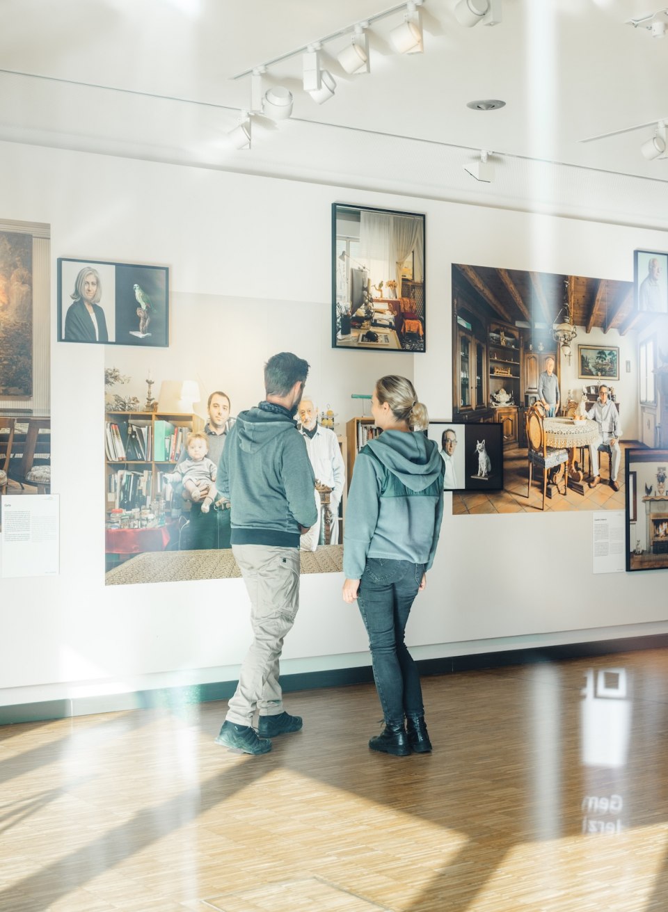 Twee bezoekers bekijken foto's op een muur in de tentoonstelling in het Max Hünten Haus in Zingst.