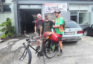 In the foreground a bicycle with red luggage, behind it Reinhard Klette with two Polish citizens. // &copy; Reinhard Klette