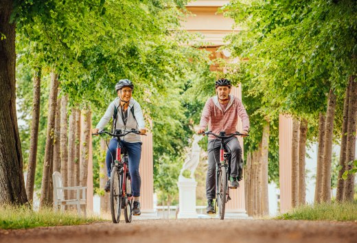 Cycling through Neustrelitz - a couple rides through an avenue // Cycling through Neustrelitz along the avenues // © MV-T/Tiemann Cycling through Neustrelitz - a couple rides through an avenue