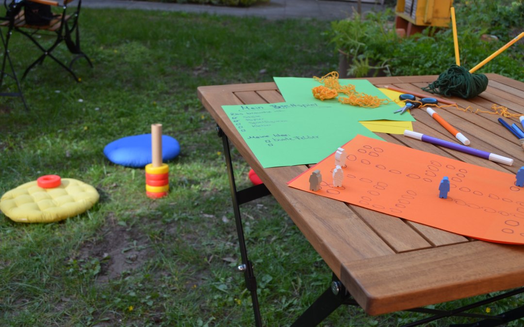 Er liggen verschillende knutselmaterialen zoals pennen, papier, garen en scharen op een tuintafel. De tafel staat op het grasveld op de binnenplaats van de stadsbibliotheek., © Stadtbibliothek Stralsund