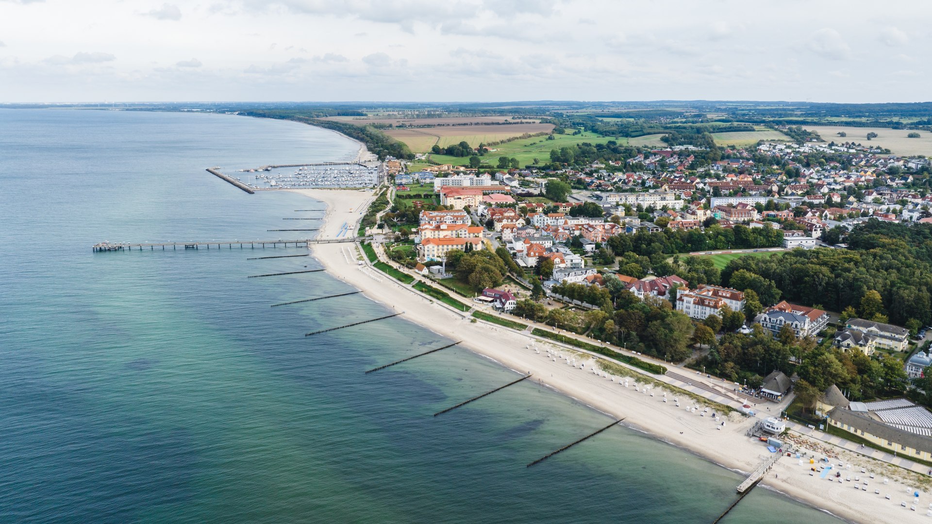 Aerial view of the Baltic seaside resort of K&uuml;hlungsborn with beach, pier, promenade and red roofs along the coast.