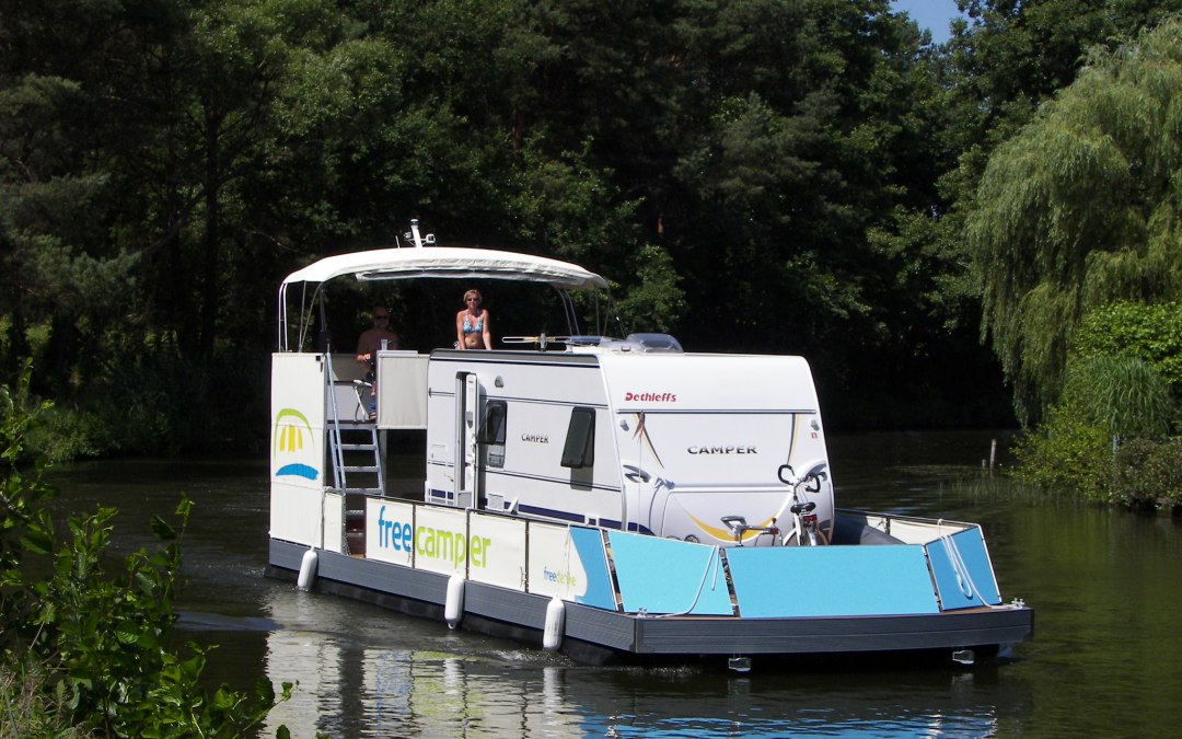 Een camper met caravan slingert door het watergebied van het Mecklenburgse merengebied., © freecamper