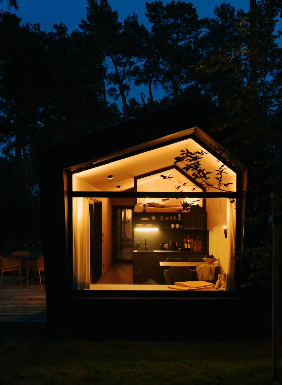Gezellig verlicht Tiny House bij nacht, met uitzicht in de stijlvol ingerichte woonkamer, midden in de natuur. // Natuur ontmoet design - stijlvol tiny house midden in het bos voor een ontspannen vakantie in comfort en rust. // © Cabin28 Gezellig verlicht Tiny House bij nacht, met uitzicht in de stijlvol ingerichte woonkamer, midden in de natuur.