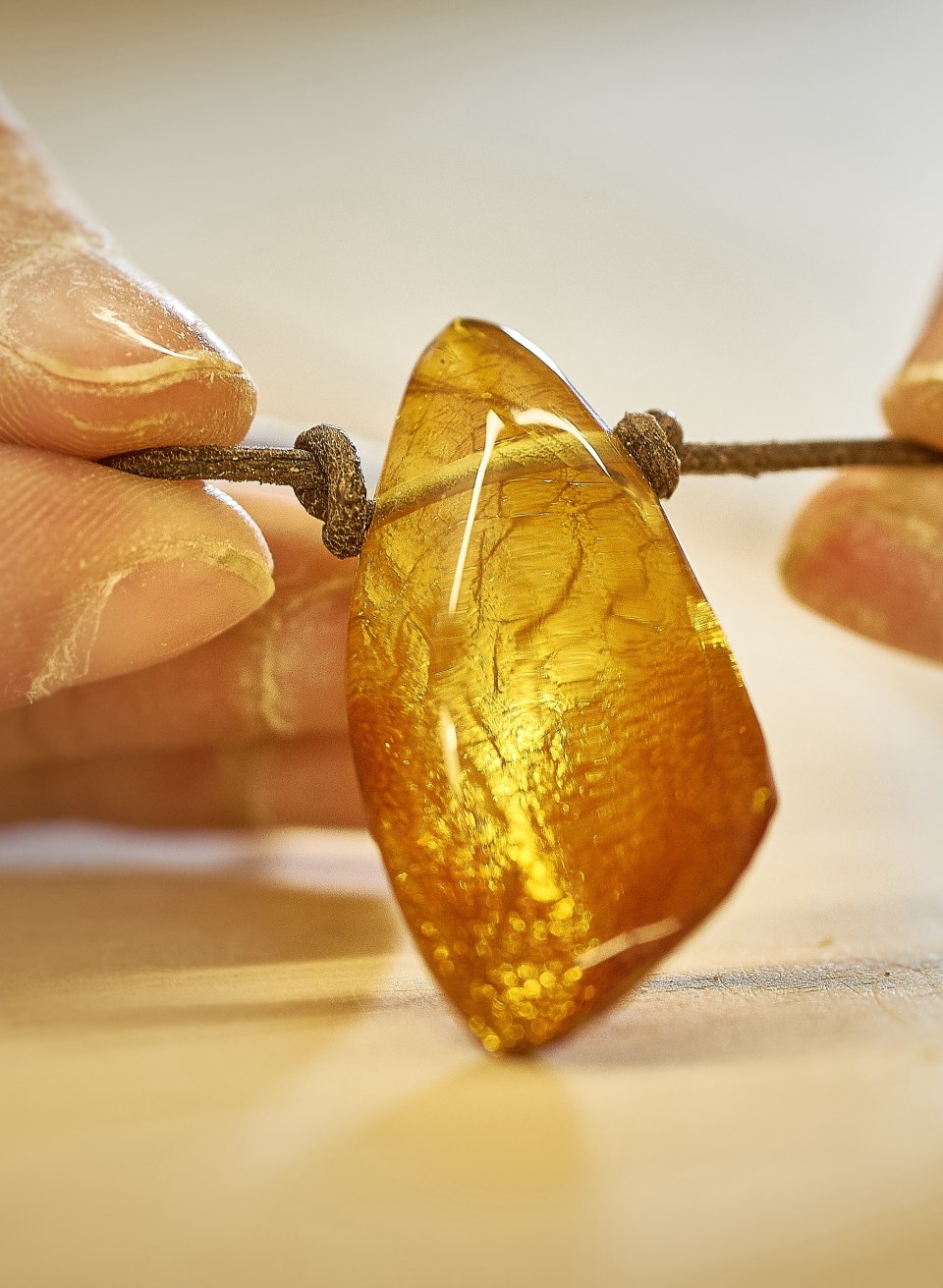 Ręce wycinają kawałek złotego bursztynu w Niemieckim Muzeum Bursztynu w Ribnitz-Damgarten.
