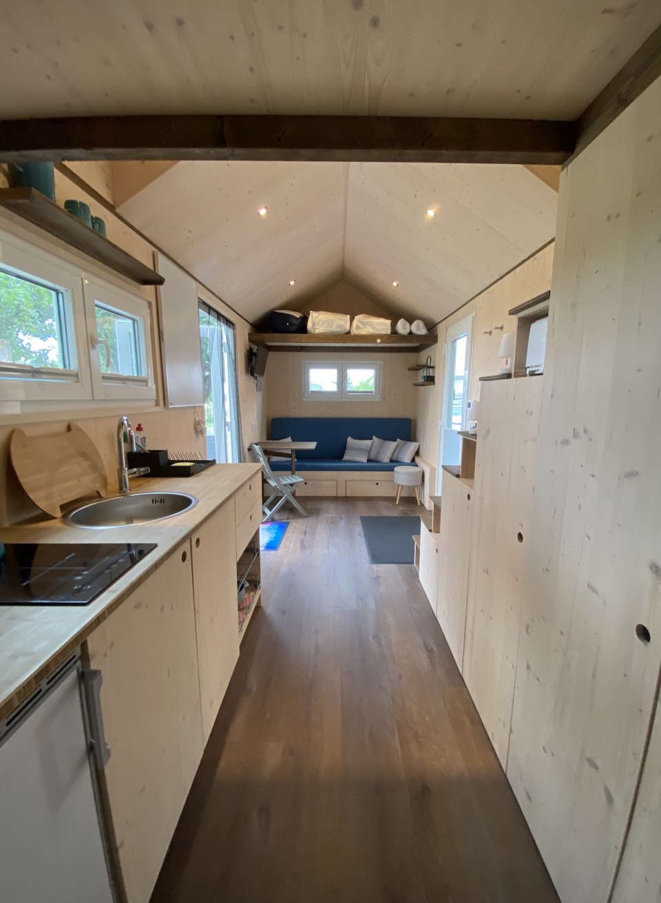 Het Tiny House van de Alpaca Idyll met faciliteiten: uitzicht naar buiten met bed, keuken en bank.