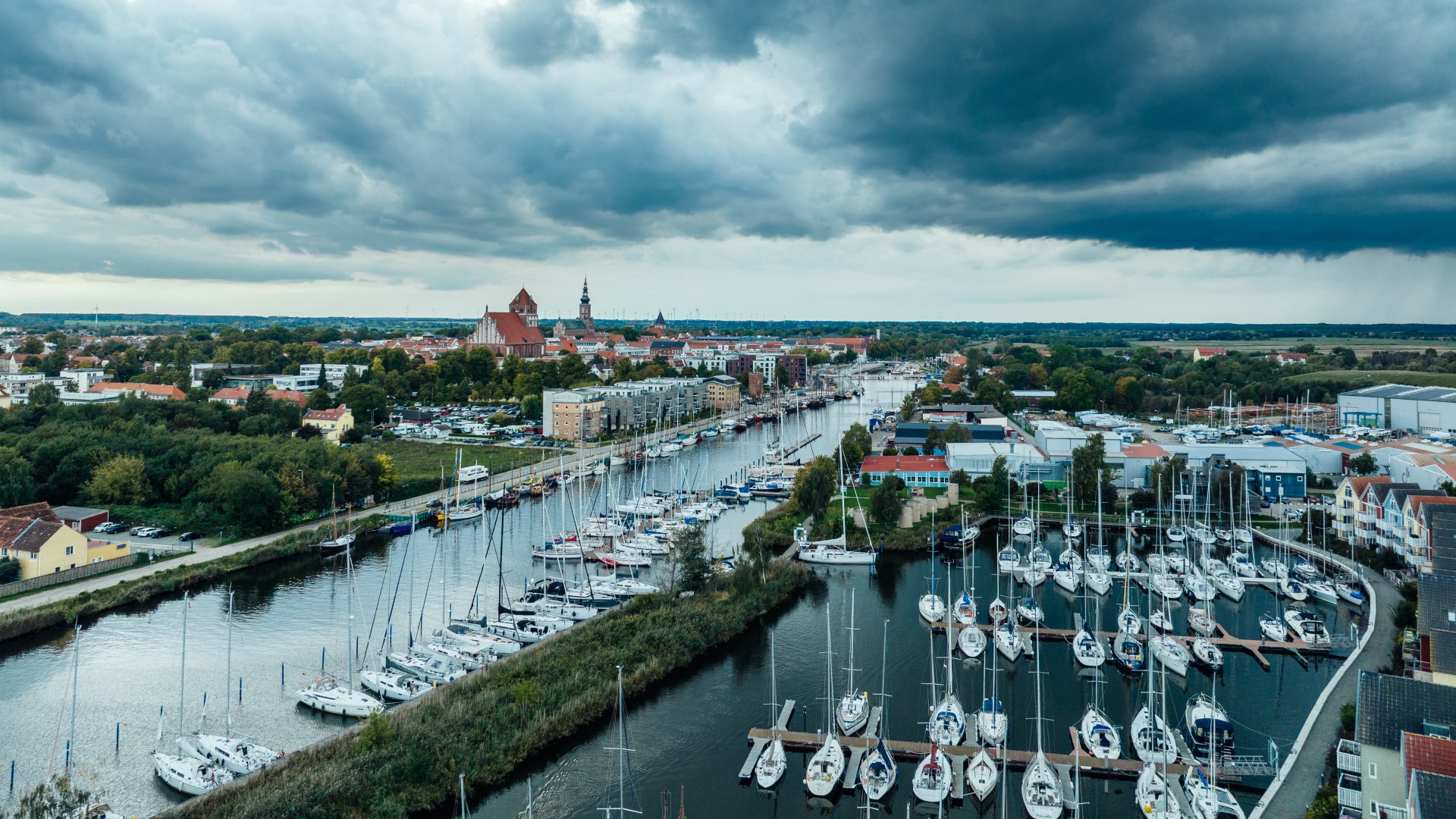 Scheepsmasten in de haven van Greifswald met prachtige wolken. De stad op de achtergrond als silhouet.