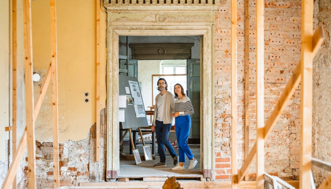 Dwie osoby oglądające wystawę w pałacu w Ludwigsburgu przez zabytkowe drzwi z ceglaną framugą.