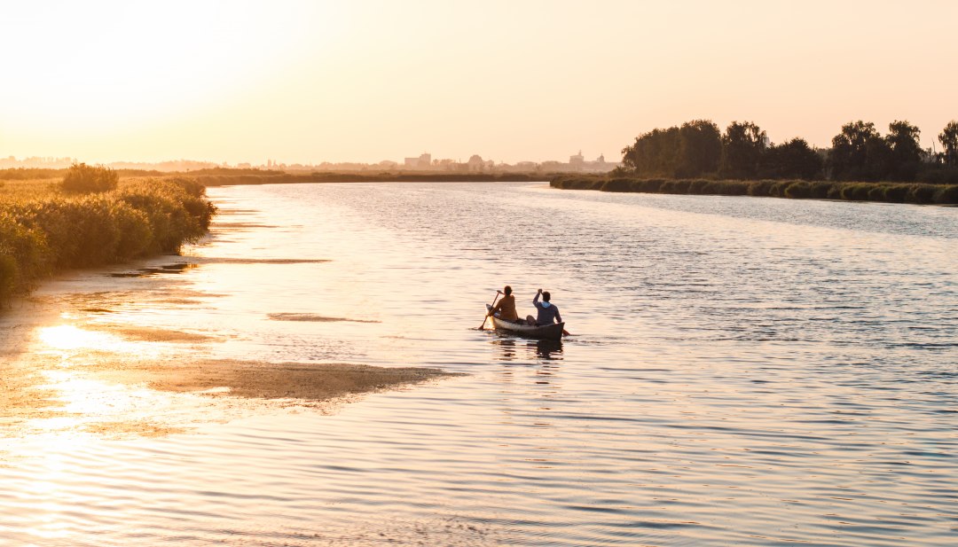 Een rustige avond op het water: twee mensen peddelen bij zonsondergang door de brede wateren van West-Pommeren, omringd door natuur en stilte.