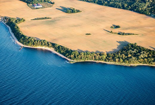 Widok z lotu ptaka na strome wybrzeże Rugii w pobliżu Glowe pokazuje kontrast między złotymi polami i turkusowym morzem, otoczonymi zielonymi lasami. // Majestatyczne klify w pobliżu Glowe na Rugii, gdzie złote pola i lazurowe morze tworzą niezapomnianą panoramę. Ogrom Morza Bałtyckiego i potężna natura największej niemieckiej wyspy inspirują do odkrywania nowych horyzontów. // © MV-T/Gänsicke Widok z lotu ptaka na strome wybrzeże Rugii w pobliżu Glowe pokazuje kontrast między złotymi polami i turkusowym morzem, otoczonymi zielonymi lasami.