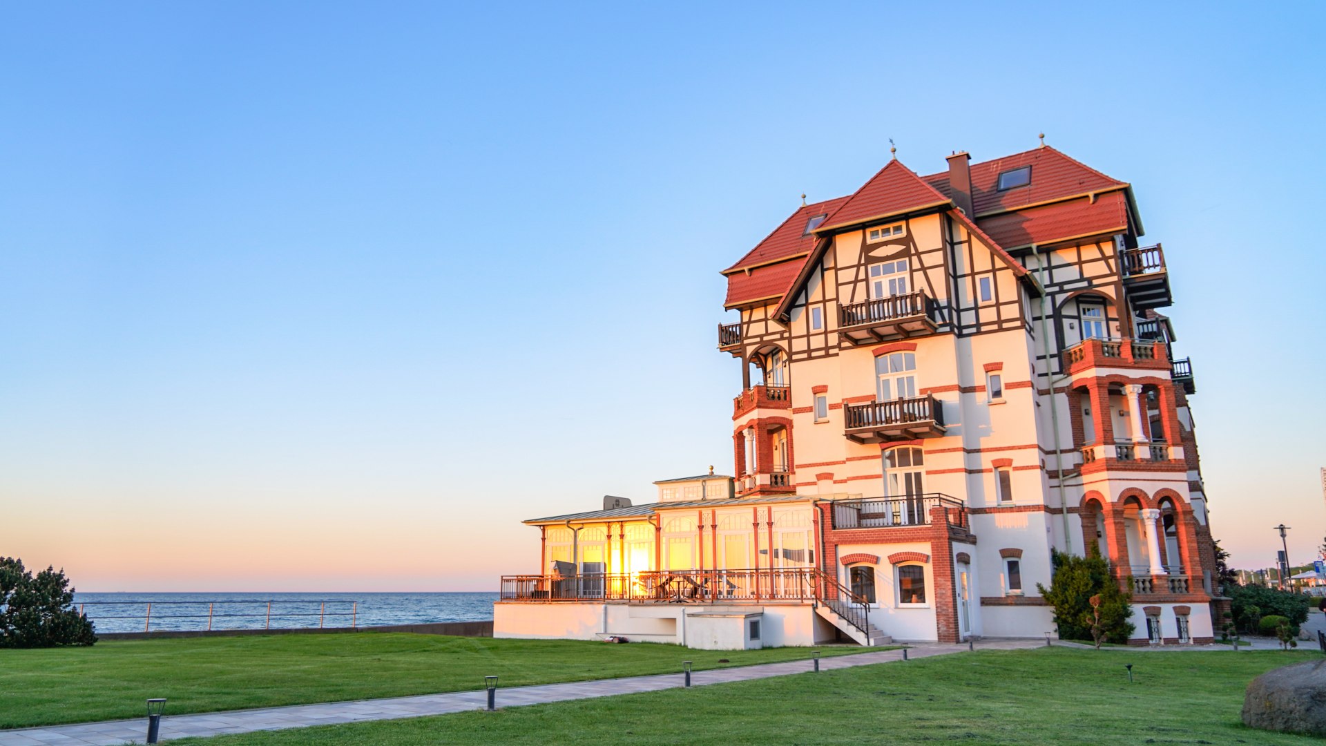 Historisch gebouw in de stijl van de kuurarchitectuur in Kühlungsborn, met vakwerk en balkons, in het avondlicht voor de Baltische Zee.
